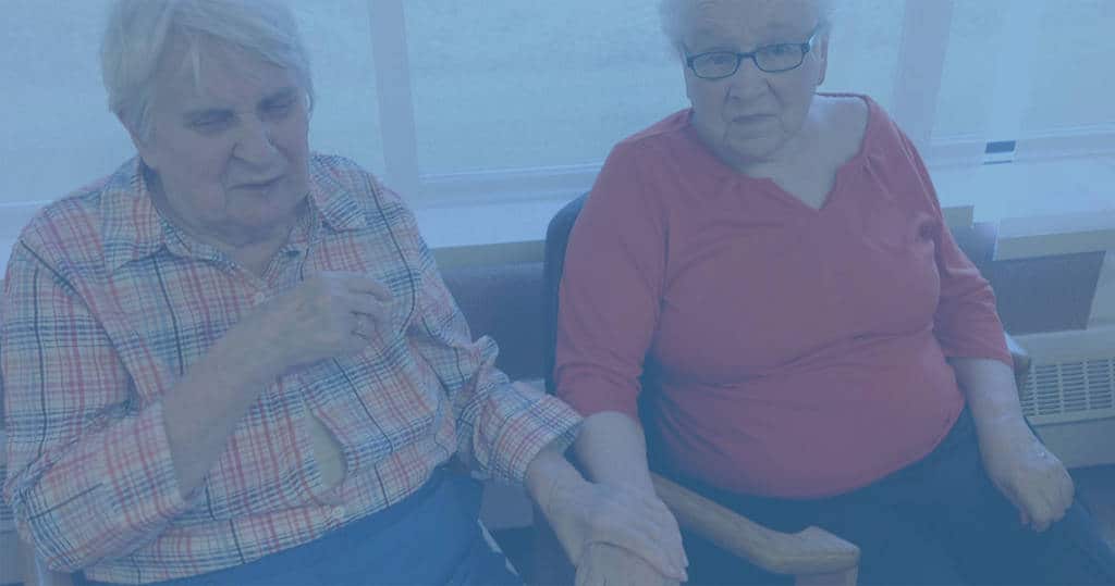 Photo of two Marianhill residents sitting together, holding hands
