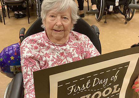 photo: elderly woman hold back-to-school poster