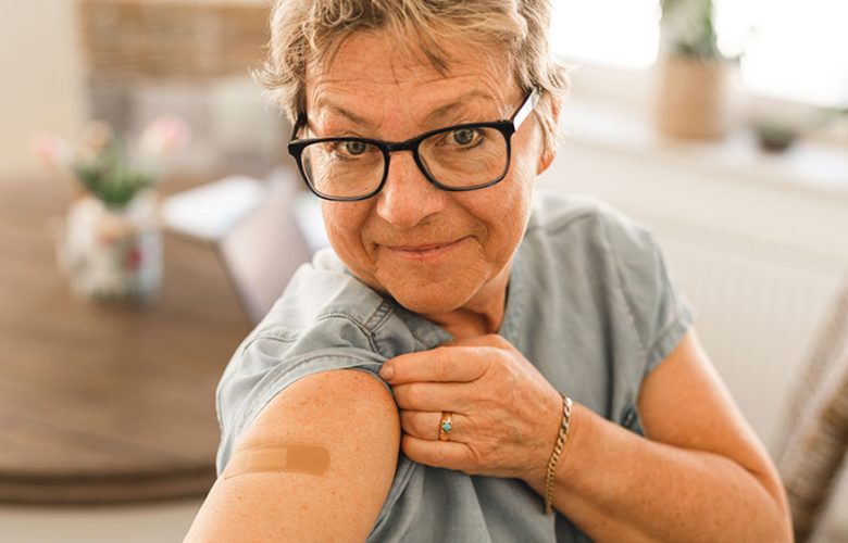 photo: woman showing her arm with vaccination bandaide