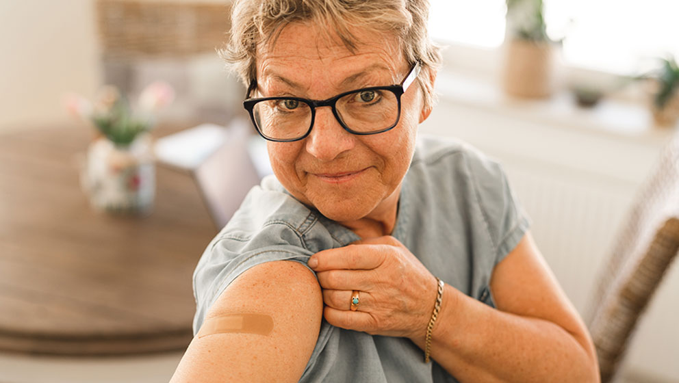 photo: woman showing her arm with vaccination bandaide